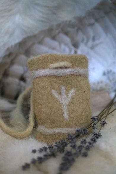 Buidel van zachtgeel vilt met een witte Algiz rune erop.