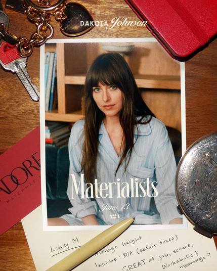 Promo pic for The Materialists which starts June 13th.
We see a picture of Dakota Johnson as her character in a light blue pyjama top with white stripes, sitting crosslegged on a couch, her dark brown hair open. The picture lies on the surface of a wooden table. Next to it lie a red calling card with the name "ADORE - Matchmaking" on it, an engraved silver pocket watch, keys on a key chain with a golden heart, a white pen, a red journal with leather binding and a piece of paper with handwriting on it saying: "Lucy M.: Average height. Income: 80k (before taxtes), GREAT at job, secure, workaholic?" The last word says "marriage?" but is struck out.