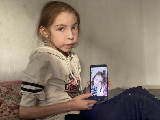 Rahaf Ayad, 12 ans, tient un téléphone montrant une photo d'elle-même avant la guerre, dans la maison de sa famille à Gaza, le 2 mai 2025.