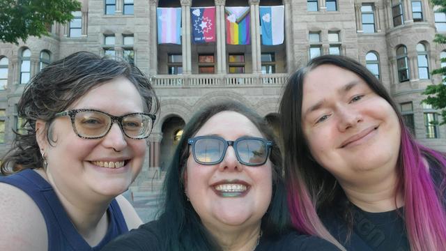 Three adorable queerdos standing in front if the SLC City & County Building, which is displaying the new official city flags.

"Each of the new designs maintains the tri-symmetrical Sego Lily symbol that serves as the traditional city flag's canton, but with the blue-and-white background replaced with the imagery of the Juneteenth Celebration, LGBTQIA Belonging and Transgender Visibility flags."