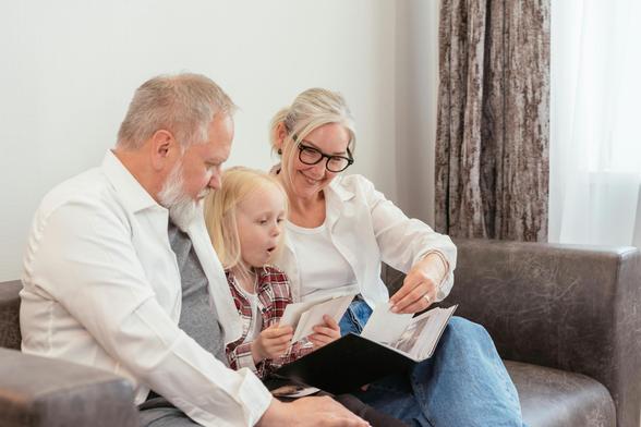 Photo de grands-parents qui font lire leur petite fille.