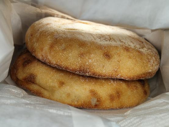 Two fairly thick potato flatbreads in a paper bag.
