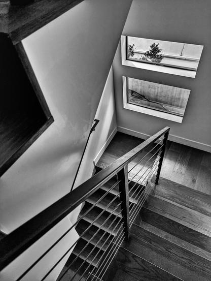 Black and white photo of a modern house interior with a banister and stairs.
