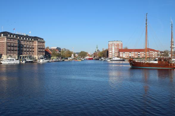 Hafen mit ein paar Yachten, einem Segelschiff im Vordergrund und weiteren Schiffen in der Ferne. 