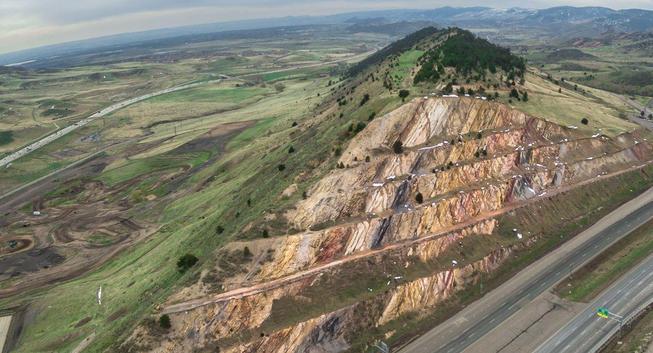 Carretera construida a través de una colina, cortándola y mostrando las capas de su interior dispuestas en ángulo con la superficie.