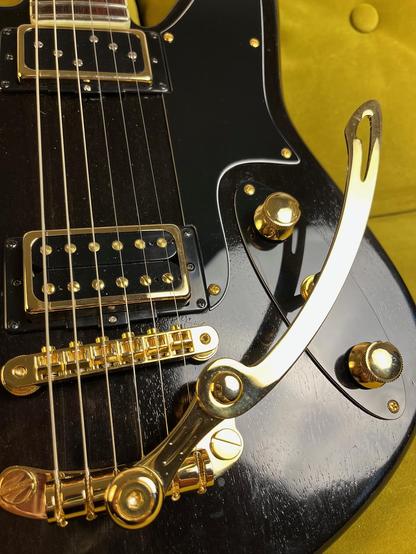 Detailaufnahme eines schwarzen Bodies einer E-Gitarre im Retro Stil mit goldener Hardware.