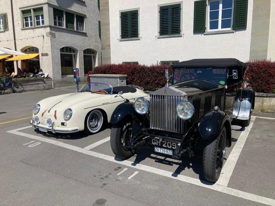 Ein Porsche 356 Speedster und ein noch älterer Rolls Royce parken unweit des Rheinufers.