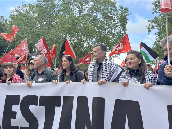 Pancarta de Izquierda Unida. En primera plana se puede ver a Antonio Maíllo, Sira Rego, Carolina Cordero, Enrique Santiago, Nerea Fernandez y Fran Pérez. Detrás de la pancarta y ondena banderas rojas de IU y palestinas. Algunos manifestantes llevan el keffiyeh palestino.