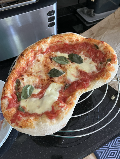 An almost heart-shaped pizza with tomato sauce, mozzarella and basil. 