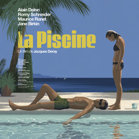 Alain Delon lying on the side of a swimming pool with his hand in the water. Rom Schneider stands next to him looking down at him.
There is a palm tree on the left and a deep blue sea in the background
