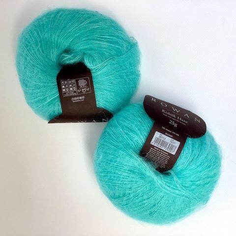 Flat lay view of 2 balls of bright turquoise kid-silk yarn on a white background.