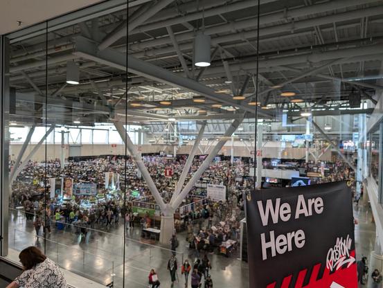 A second floor view of the Tabletop Hall at PAX East 2025. Gamers seated playing games, or standing at booths.