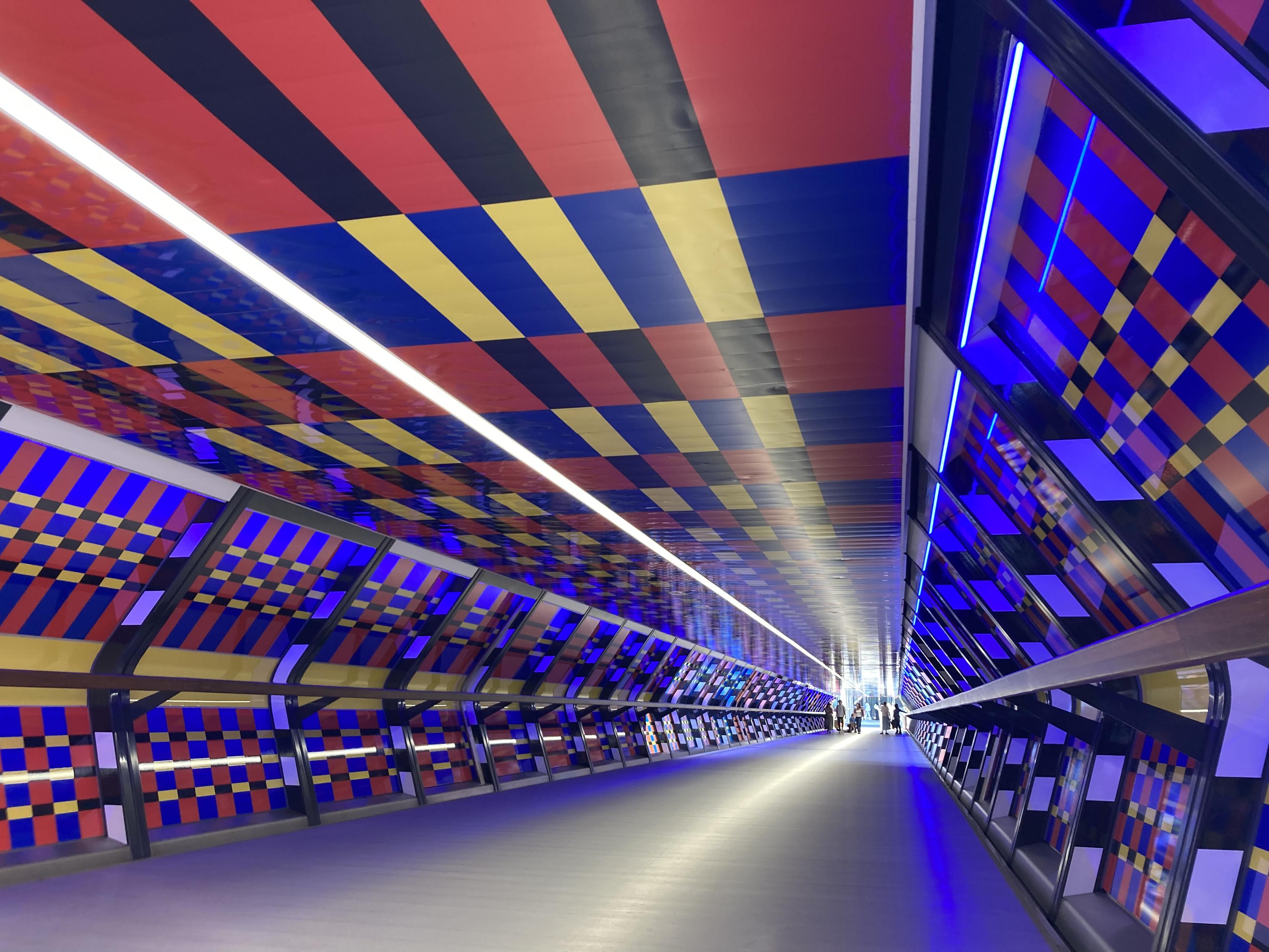 the colourful bridge over Adam's Place in Canary wharf, with a geometric pattern on the walls and ceiling
