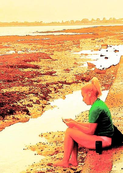 Heavy use of filters here transform a person, in beach ware, reading on a concrete ledge adjacent to the foreshore of an estuary .. the image is bleached orange & yellow principally.. and the person made a sorta ghosly presence ..