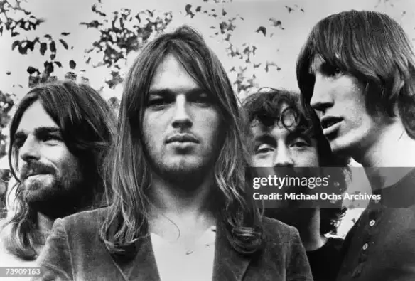 Pink Floyd - Publicity Shot (1973)
Photo légendaire du groupe britannique Pink Floyd prise en 1973, capturant les membres du groupe dans une pose intemporelle. L’image montre (de gauche à droite) Rick Wright (claviers), David Gilmour (guitare), Nick Mason (batterie) et Roger Waters (basse) — chacun dans une attitude calme et contemplative, à l'image de leur musique. Cette photo symbolise l'apogée du groupe, peu avant la sortie de leur chef-d'œuvre The Dark Side of the Moon, un album qui allait révolutionner l'histoire de la musique.