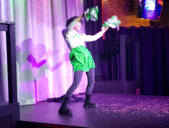 Austin Tacious, still dressed as Gerard Way as a cheerleader, waving pompoms around his head.