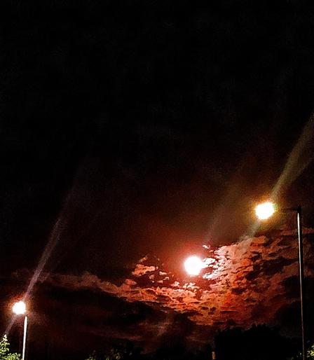 ..another study of the moon in redish tints..this time held between two street lights on the right & left sides of the image..clouds occupy space under the moon, & between these artificial lights, of contrasting shadows & highlights..