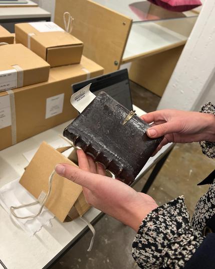 Een klein leren boekje in een hand.