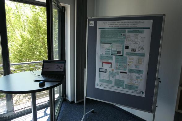 Photo showing demo laptop and poster with title "Hands-on semantic data management with LinkAhead: Increased data findability and reusability"