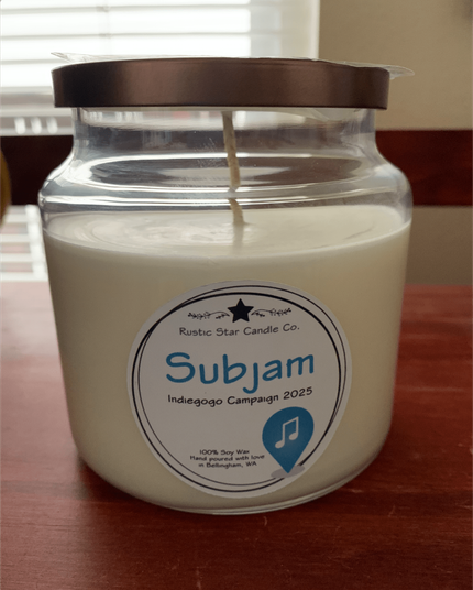 A 16oz glass-jarred soy wax candle with a custom Subjam label, indicating the Indiegogo 2025 campaign.