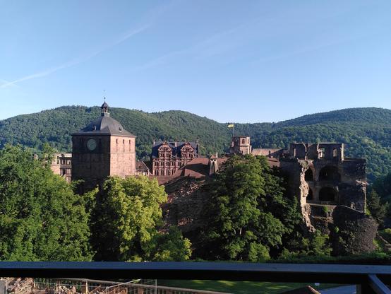 Heidelberger Schloss vor Heiligenberg im Hintergrund unter blauem Himmel.