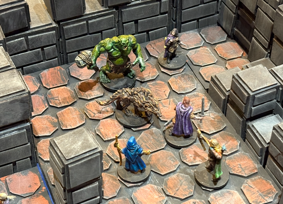 A scene of miniatures showing a party of four adventurers - a swordsman, an archer, a Druid, and a rogue- facing off against an ogre and his warg companion.