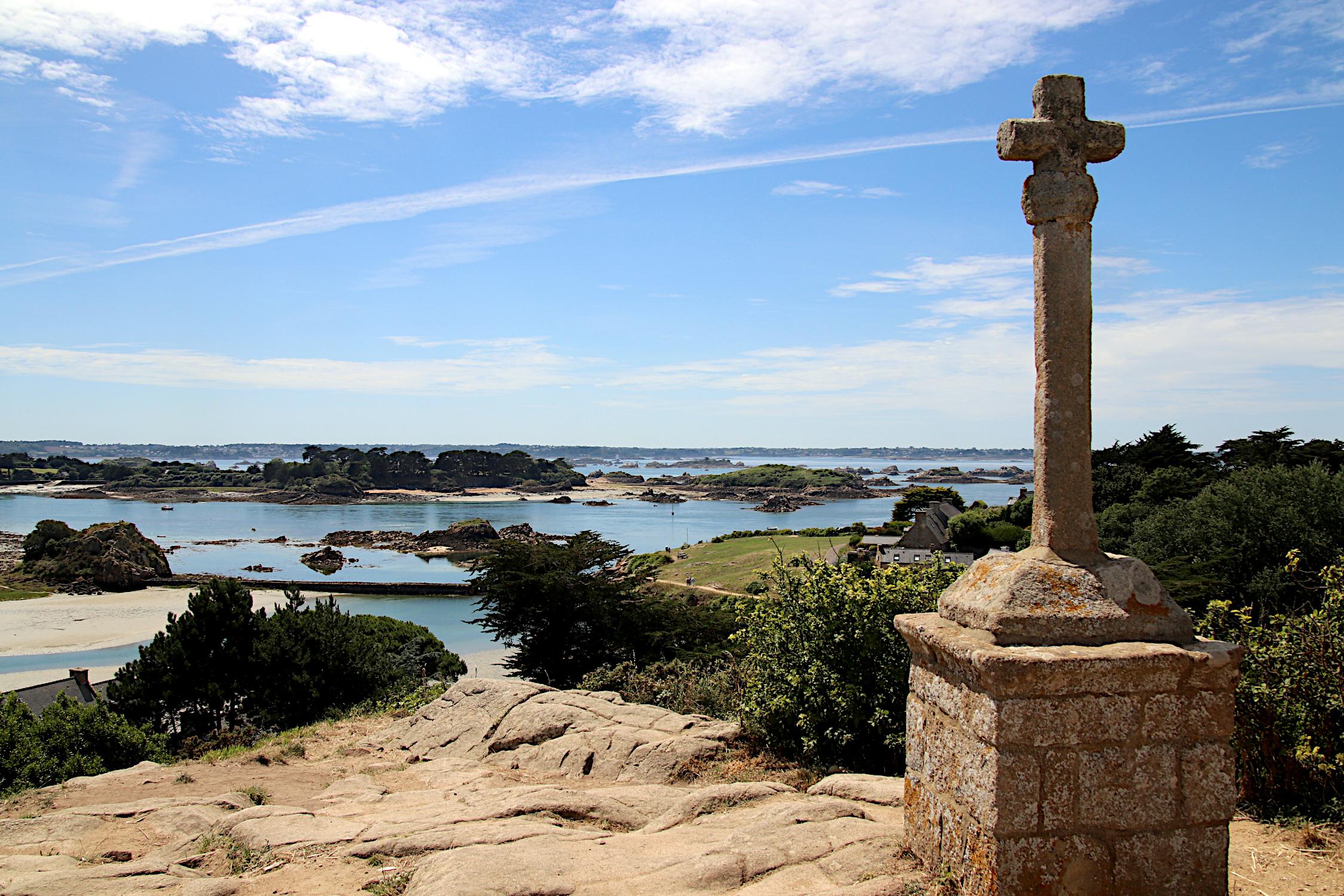 Der Betrachter steht auf der Île de Bréhat an der Bretonischen Küste und blickt auf das Meer. Vor der Küste sind viele kleine, felsige Inseln zu sehen. Im Vordergrund steht ein steineres Kreuz auf einem steinerenen Sockel. Der Betrachter steht auf der Île de Bréhat an der Bretonischen Küste und blickt auf das Meer. Vor der Küste sind viele kleine, felsige Inseln zu sehen. Im Vordergrund steht ein steineres Kreuz auf einem steinerenen Sockel.