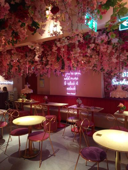 Café interiour - tables, chairs and a sofa. Ceiling decorated with loads of pink flowers.