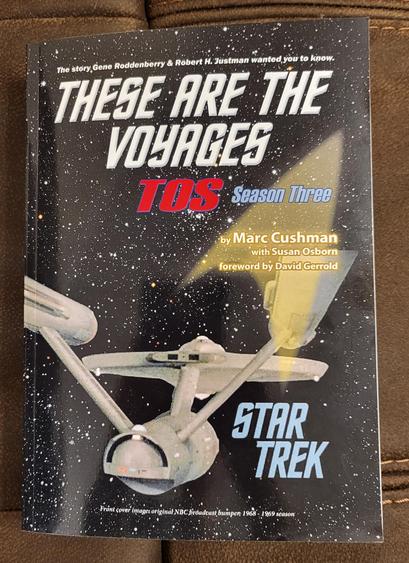 The cover of These are the Voyages: TOS Season Three. Pictured is a classic SFX shot  of the Enterprise flying away so there's a good view of the shuttle bay doors, Impulse engines, and rear of the warp nacelles.