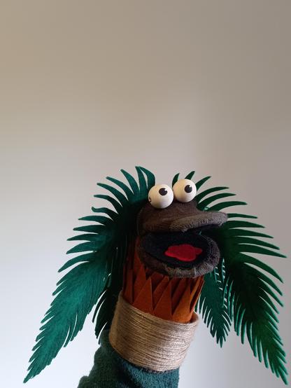 Foto a Nina la palmerina, la palmera marioneta de mano. Está como hablando y mirando hacia la derecha.