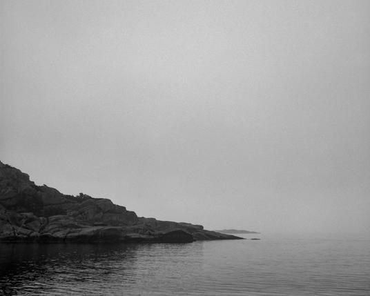 Rocky shore sloping into the sea on a very foggy day.