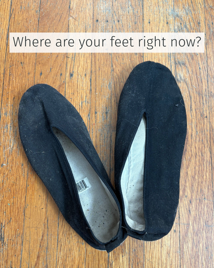 A pair of worn black tai chi shoes rest on a wood floor, angled naturally and slightly askew. The shoes are scuffed and dusty—clearly used. The overlaid text reads: “Where are your feet right now?”

