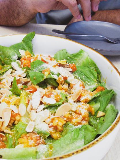 A plate of green salad topped with almonds and grape slices
