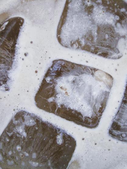 A top view, close-up shot of ice in a glass of coffee 