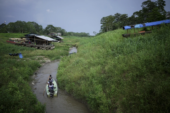 People on canoe going through a river surrounded by grass