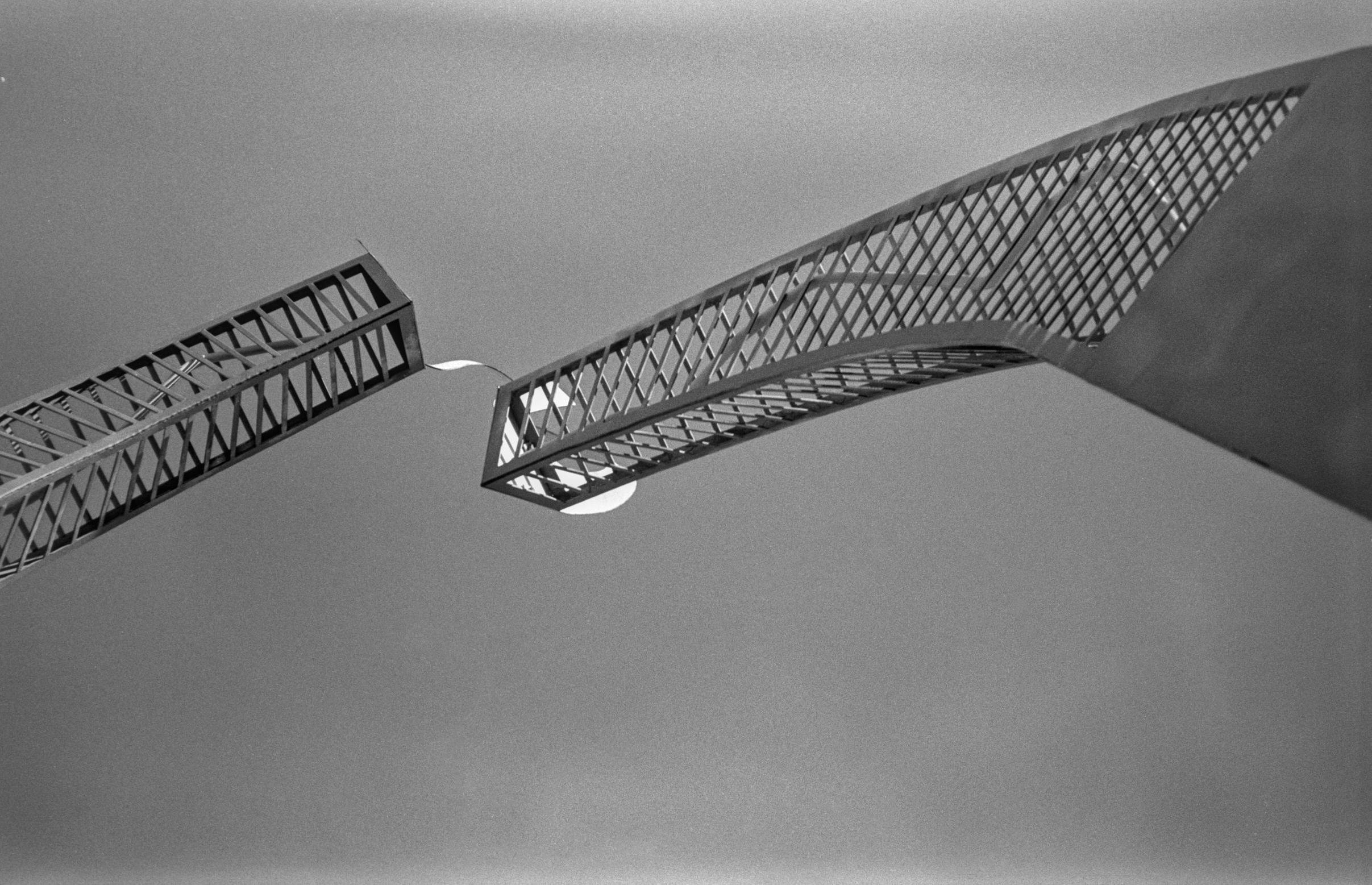 On the monochrome photo two metal elements of the art-object in the form of arcs on the sky background. On the monochrome photo two metal elements of the art-object in the form of arcs on the sky background.