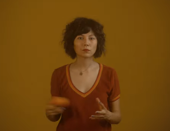 Steady Holiday dressed in dark orange on an orange background playing with a tangerine.