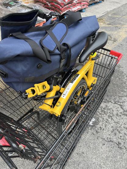 my bright yellow Brompton folding bike all folded up and placed inside a shopping cart at the grocery story. The blue bag on top is a large bag for carrying all kinds of things, specially made for the Brompton line. 

The whole setup is a game-changer for me. 