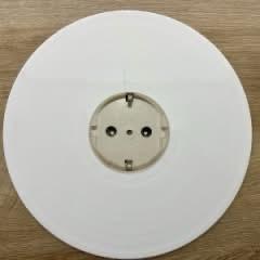 Eine leere weiße Schallplatte, die auf einer hölzernen Unterlage ruht und in der Mitte eine Nabe mit Löchern für einen Plattenspieler aufweist.