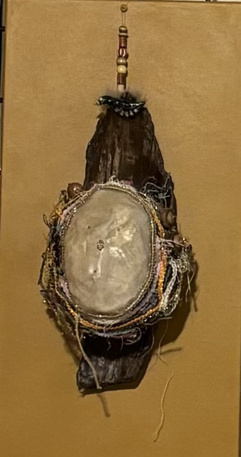  A bird’s nest mounted on a piece of driftwood and covered by a paper mache mask that can be lifted.