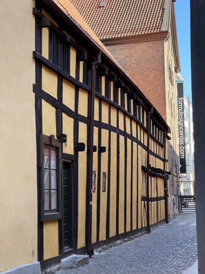 A half-timbered house front down the side of a cobbled street.