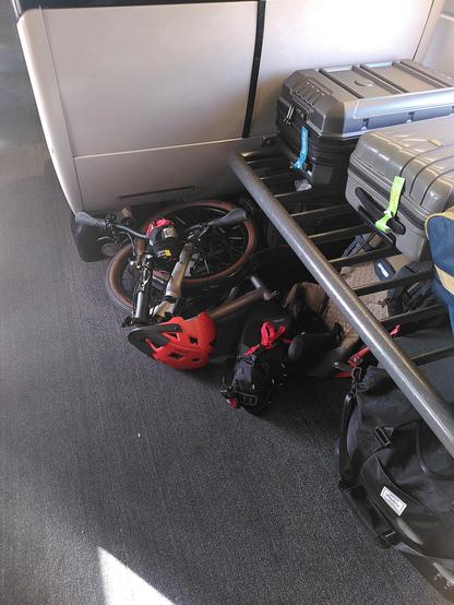 Mon vélo plié posé par terre dans le coin du porte bagage à l'étage dans une voiture 1er classe