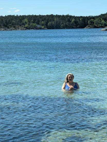 A sea mermaid posing in clear blue ocean water