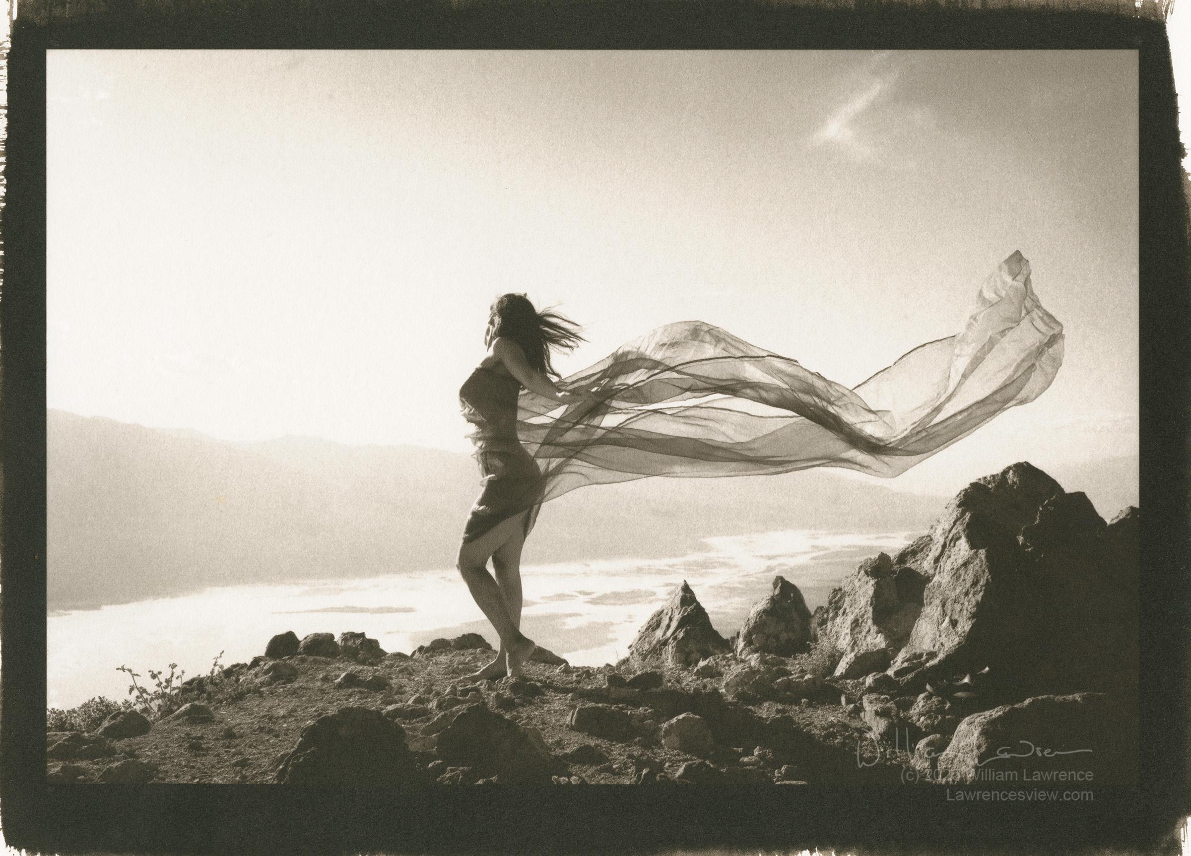 Model Kayla poses wrapped in fabric on Dante's Peak in Death Valley - the valley floor can be seen below. Kayla's fabric wraps around her body and flies out in the breeze. Model Kayla poses wrapped in fabric on Dante's Peak in Death Valley - the valley floor can be seen below. Kayla's fabric wraps around her body and flies out in the breeze.