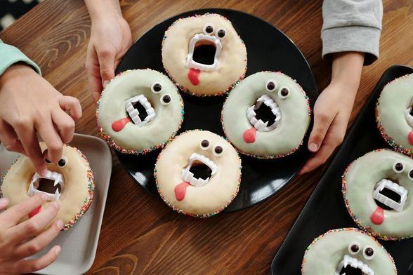 Overhead view of novelty doughnuts with candy eyes and plastic vampire teeth placed in the center.