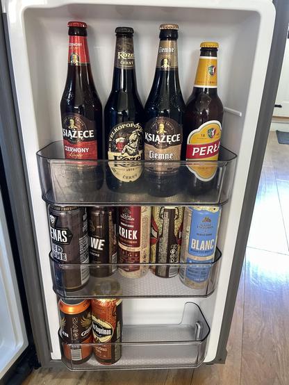 The fridge door mostly filled with bottles and cans of different beers.