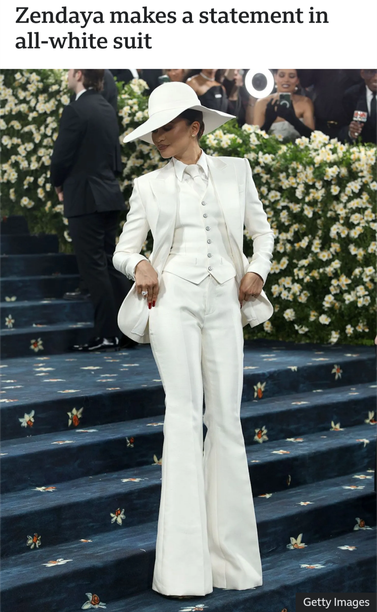 Image: Zendaya in white suit making and entrance on stairs at Met Gala 2025.