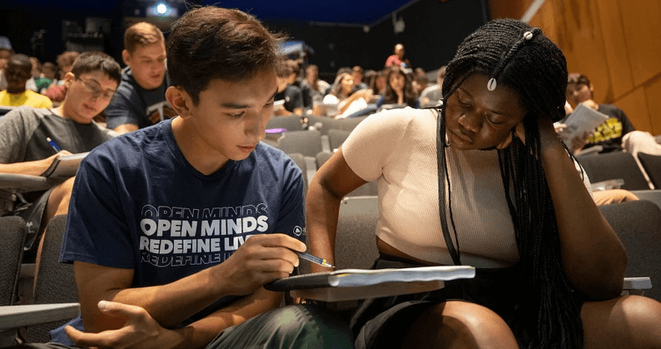 switching to active learning: a photograph of two students sitting next to each other in a classroom looking at a set of notes together