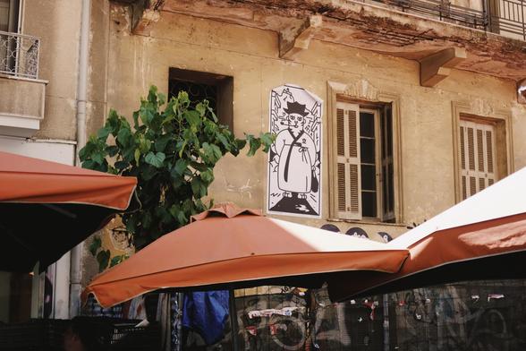 A close-up of an old building with peeling paint and a black-and-white street art poster of a tiger strolling through a market scene.