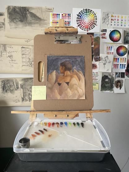 Easel and pallet setup with an unfinished painting of a women enveloped in flower, looking away. 